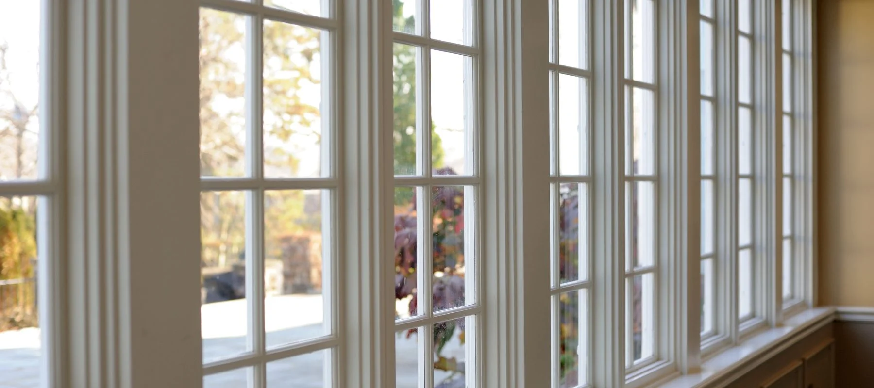 Row of white-framed French-style windows letting in natural light with an outdoor view