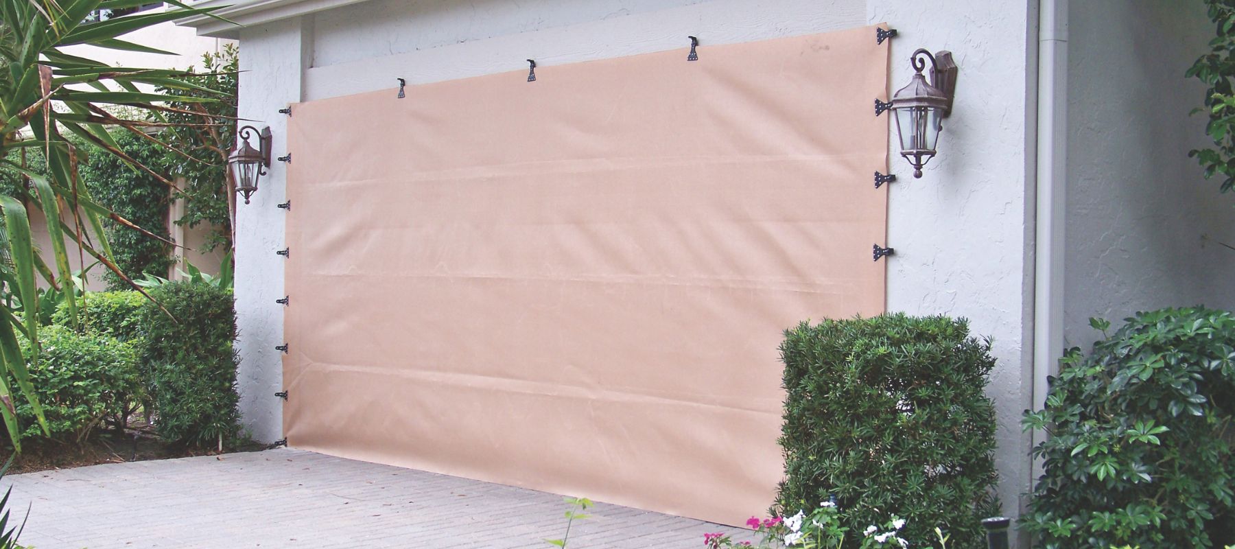 Tan fabric storm shield installed over a garage door for hurricane protection