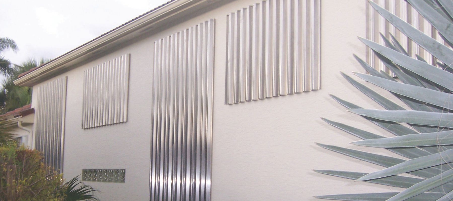 Corrugated metal storm panels securely fastened over house windows