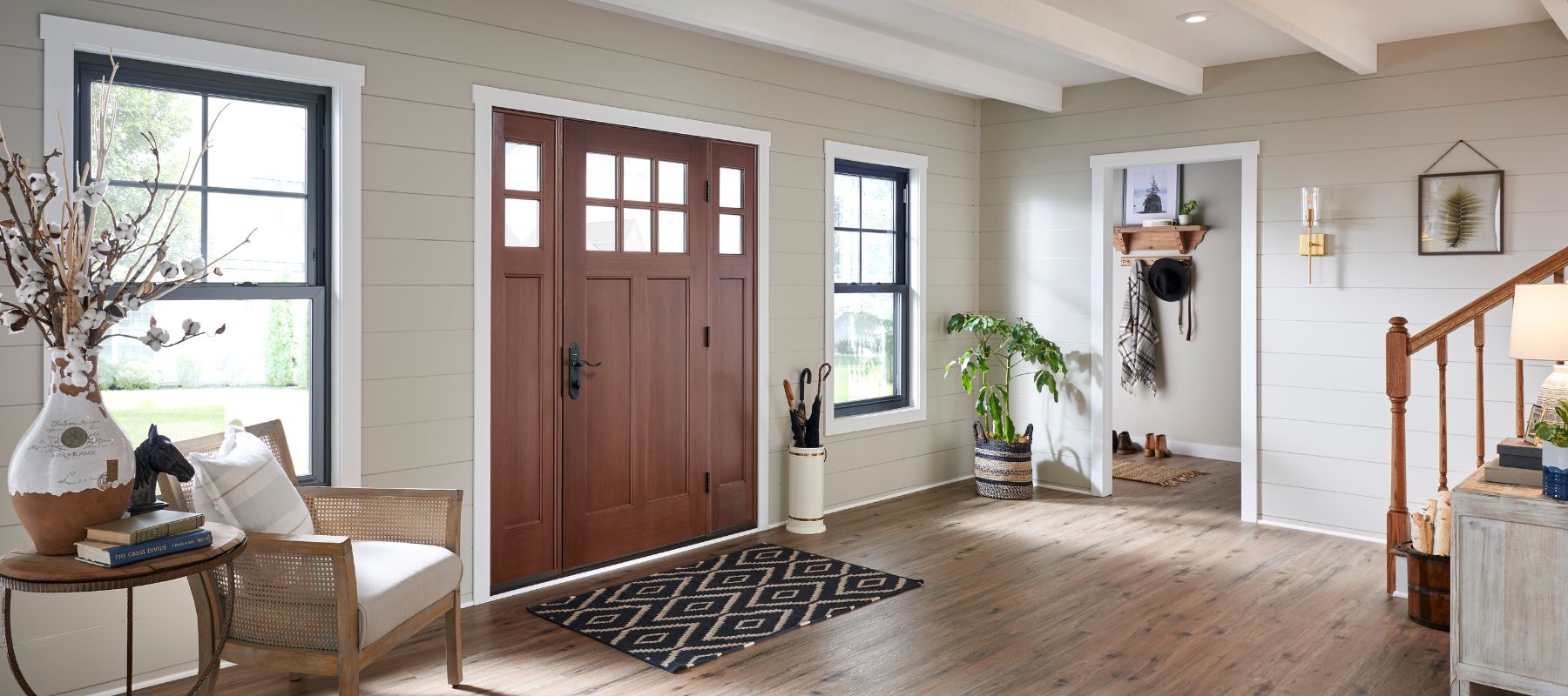 Cozy and stylish entryway featuring a wooden front door, armchair, and decorative accents