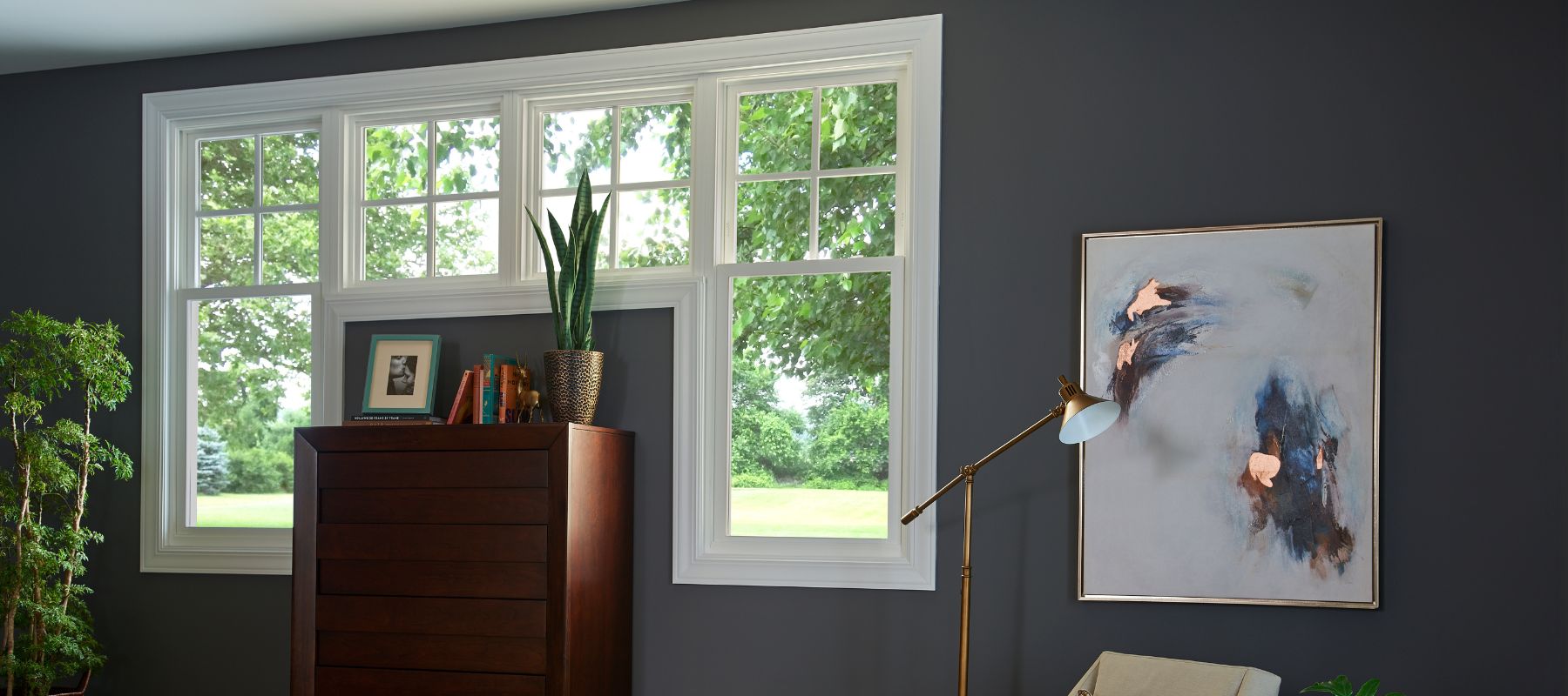 Contemporary living room window with white frames, plants, artwork, and a dark-painted wall
